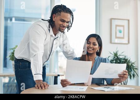 All looks good so far. two businesspeople going through paperwork together in an office. Stock Photo