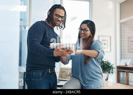 Exploring all their options with ease. two businesspeople using a digital tablet together in an office. Stock Photo