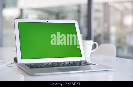 Now that weve got your attention...a laptop with a green screen on a desk in a modern office. Stock Photo