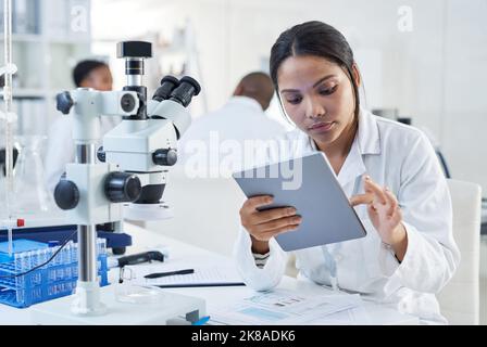 Making broader use of digital tools in the lab. a young scientist using a digital tablet in a lab. Stock Photo