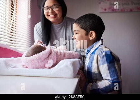 Its true, big brother really is watching you. an adorable little boy bonding with his newborn sister in the bedroom at home. Stock Photo