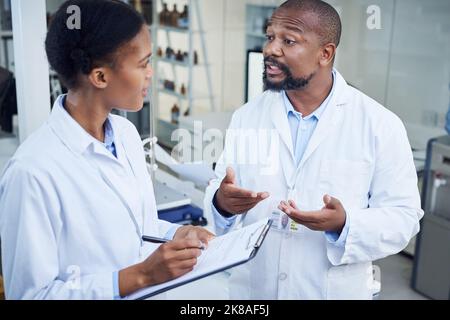 Working hard to crack the case. two scientists having a discussion in a lab. Stock Photo