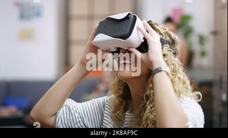 The future doesnt seem so distant anymore. a young businesswoman using a virtual reality headset in a modern office. Stock Photo