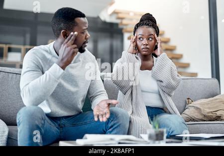 Dont let debt derail you. a young couple looking stressed while working on their finances at home. Stock Photo