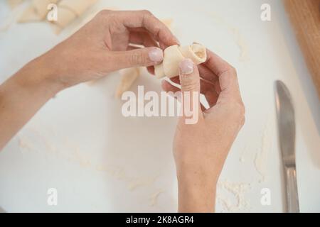 Woman in hands holds a croissant blank from cooked dough Stock Photo