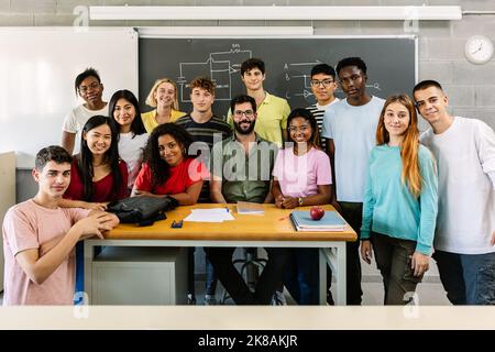 Large group portrait of millennial students with male teacher in classroom Stock Photo