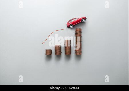 Increasing petrol price concept, business chart stacks of coins with toy car moving upwards Stock Photo