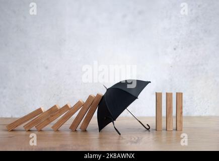 Umbrella protecting wooden dominoes insurance concept Stock Photo