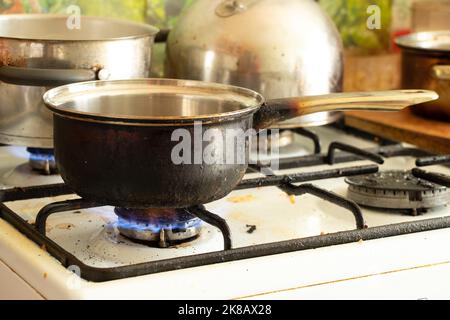 a dirty saucepan stands on a dirty gas stove in the kitchen at home, cooking soup on the stove, gas stove, kitchen Stock Photo