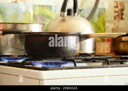 a dirty saucepan stands on a dirty gas stove in the kitchen at home, cooking soup on the stove, gas stove, kitchen Stock Photo