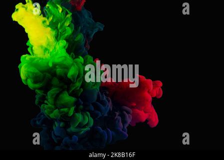 Green red and blue inks in water making abstract wallpaper on black banner. Stock Photo