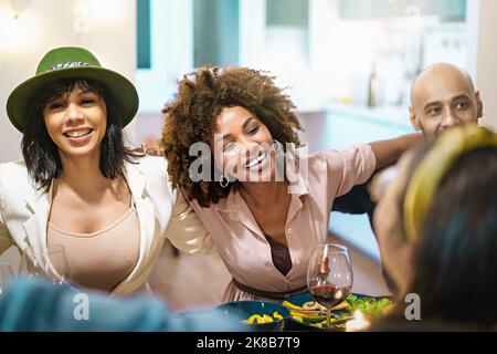 Multiracial, diverse people bonding at dinner table smiling, having fun and spending joyful time together - multiethnic people embracing dining and dr Stock Photo