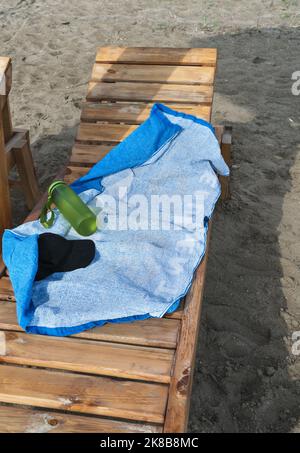 sunbathing accessories lying on wooden sunbed at the beach Stock Photo