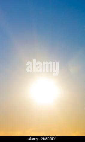 Blurred background. Sun in sky. Bright sun with sunbeams shines on clean yellow blue sky. Bright sun light, sun ray lens flares, sunshine day, sunny light, sunshiny boke. Beautiful natural background Stock Photo