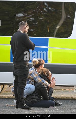 Washington Drive, Birmingham - October 22nd 2022 - A woman collapsed onto the ground with grief crying out for her "brother" who was stabbed and killed on Washington Drive in Handsworth Wood just after 11pm last night (21 Oct). The 29-year-old victim, named locally as "Jamie" was stabbed to death. The woman was consoled by a family friend as she screamed out in agony. Floral tributes and bottles of beer were left at the scene along with heartfelt messages from friends and family. Credit: Scott CM/Alamy Live News Stock Photo
