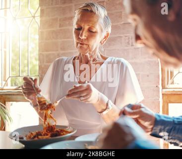 Old couple eating pasta at restaurant together on a date celebrating anniversary. Food, romantic dinner and senior man and woman enjoying spaghetti in Stock Photo