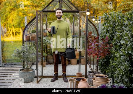 Stylish guy with watering can in garden Stock Photo