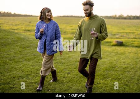 Couple hang out together, walking on green field on sunset Stock Photo