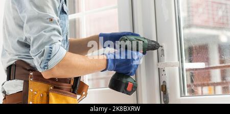 master with a screwdriver sets fittings on the window Stock Photo