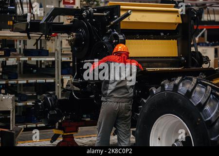 Industrial workers assembles agricultural harvester in workshop. Stock Photo