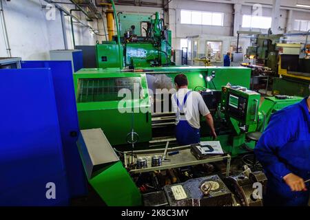 Factory engineer adjusting operation parameters of CNC lathe machine. Stock Photo