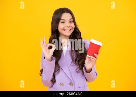 Teenage girl with take away cup of cappuccino coffee or tea. Child with takeaway cup on yellow background, morning drink beverage. Happy face Stock Photo
