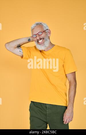 Smiling older bearded hipster man standing isolated on yellow background. Stock Photo