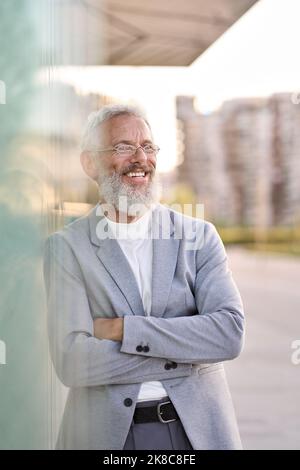 Smiling happy senior old business man wearing suit standing outdoor, portrait. Stock Photo