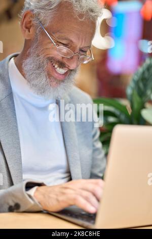 Happy older senior business man using laptop working late on computer. Stock Photo