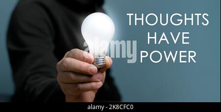 Hand holding light bulb with text Thoughts Have Power, The power of thinking ideas, think big. Stock Photo