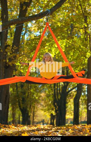 Woman practicing aerial silks on a trees background in autumn Stock Photo