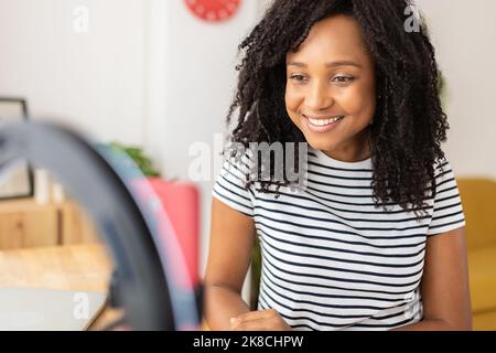 Young adult brazilian blogger recording video with mobile phone at desk Stock Photo