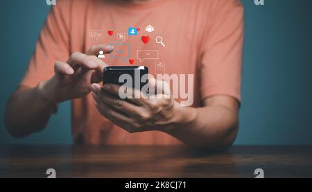 Man using smartphone with social media icons, love, search, people, group, shopping, document. Mobile Phone application and social media marketing con Stock Photo