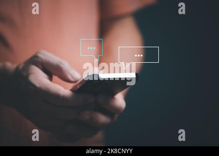 Man hands using smartphone texting Live chat chatting and social network concepts, chatting conversation working at home in chat box icons pop up. Soc Stock Photo