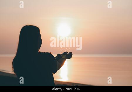 Silhouette of praying hands with God facing the sky at sunrise morning on the beach, Faith in religion and belief in God, Power of hope or love and de Stock Photo