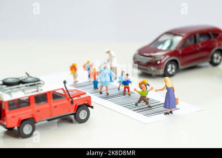 Miniature toys school kids walk on cross road bar code - school children road safety concept. Stock Photo