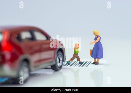 Miniature toys school kids walk on cross road bar code - school children road safety concept -  side view Stock Photo