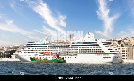 Huge cruise ship docked at terminal of Galataport, located along shore of Bosphorus strait, in Karakoy neighbourhood, with Galata tower in the background, Istanbul, Turkey  Stock Photo