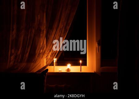 Candles on the window in an apartment in Ukraine, Ukraine without electricity due to the war, an apartment without light, the light of a candle in the Stock Photo