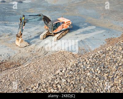 Loader wait for dump truck. Heavy machinery in the clinkstone or phonolite mining quarry. The excavators  crusher with belt conveyor puts crushing and Stock Photo