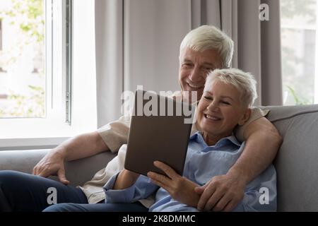 Happy affectionate middle aged family couple using digital tablet. Stock Photo