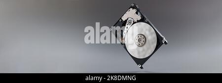 Computer hard disk drive on hook, black hardware disk, memory storage cylinder on grey background Stock Photo