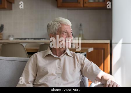 Handsome older man feels happy relaxing on sofa at home Stock Photo