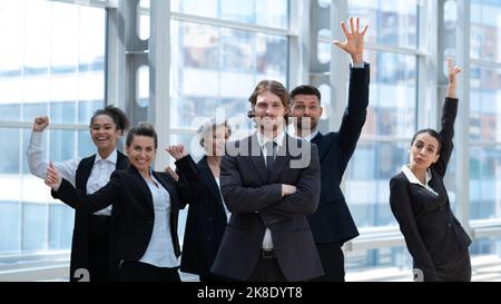 Happy business people team standing with arms raised in office building Stock Photo