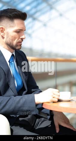 Pensive businessman drinking coffee in cafe in office lobby Stock Photo