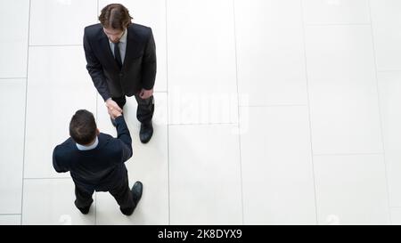 Business partners shaking hands as a symbol of unity, view from the top Stock Photo