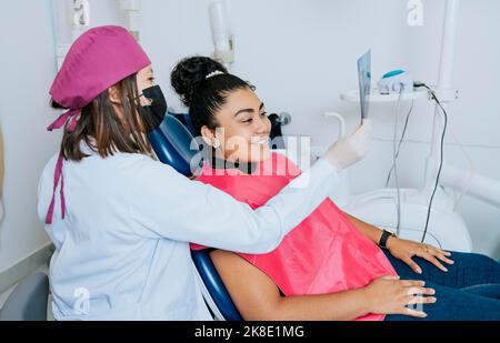 Dentist showing patient x-ray, Dentist with patient reviewing the x-ray. Patient looking at x-ray with dentist, Concept of dentist showing x-ray Stock Photo