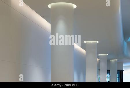 Bangkok, Thailand - Sep 30, 2022 : Concrete interior space with white round pillars arranged long lines lighting cast the shadow on the wall and pilla Stock Photo