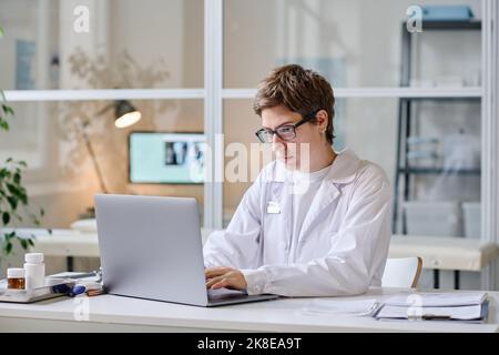 Female doctor concentrating on her online work while using laptop at office Stock Photo