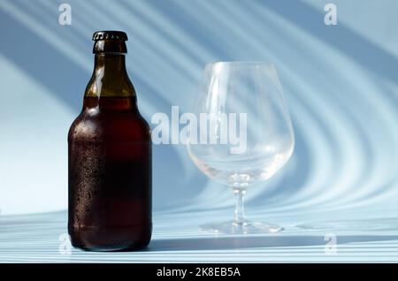 Top view of glass brown beer bottle, glass of beer against blue background close up. Food lifestyle. Alcoholic drink production. Copy space, mockup. Stock Photo